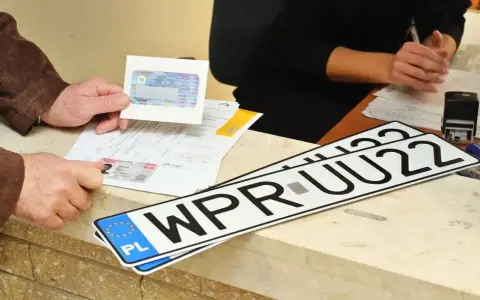 Nowe rejestracje samochodowe leżą na ladzie urzędu. Klient pokazuje dokumenty do rejestracji pojazdu.