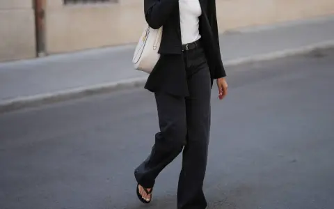 Look con blazer negro y jeans grises anchos. Bolso blanco y sandalias negras completan el atuendo.