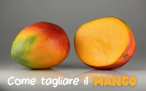 Un mango intero e uno tagliato a metà, mostrando la polpa succosa. Impara come si mangia il mango per gustarlo al meglio.