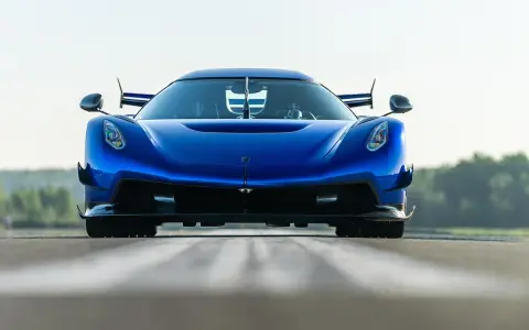 Niebieski Koenigsegg Jesko Attack z agresywnym przednim splitterem i spojlerami, gotowy do ataku na torze.