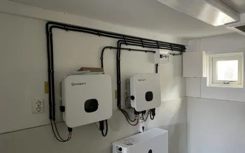 Två Growatt-växelriktare och en batteribank för solceller monterade på en vägg. Kablar dras snyggt längs väggen.