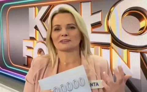Kobieta z Koła Fortuny trzyma kartę z napisem "00000", zastanawiając się, co daje złota karta w kole fortuny.