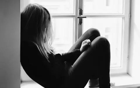 Una joven sentada en la ventana, con la mirada perdida. Un momento para reflexionar sobre qué decirle a tu hija cuando le rompen el corazón.