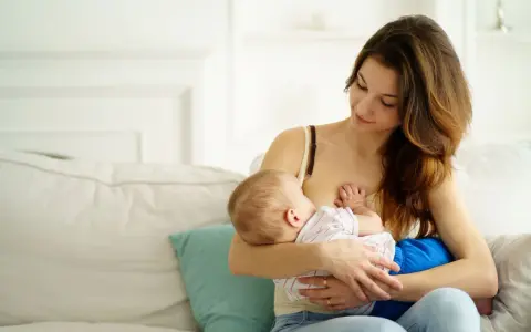 Ciepła chwila karmienia piersią. Mama z miłością patrzy na swoje dziecko, wspierając naturalną laktację.