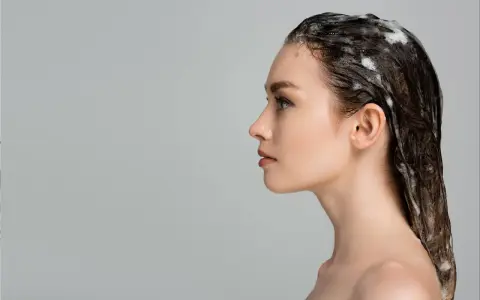 Kobieta z pianą na włosach. Zastanawiasz się, jak często robić peeling głowy? Regularne złuszczanie to klucz do zdrowych włosów.