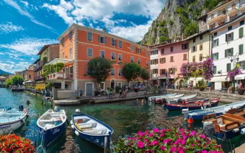 Colorate case sul lungolago di Limone sul Garda, con barche ormeggiate e fiori vivaci. Un luogo incantevole da scoprire, perfetto per capire cosa visitare a Limone sul Garda.