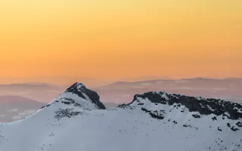 Giewont zimą o zachodzie słońca. Ośnieżone szczyty Tatr w odcieniach pomarańczy i różu.
