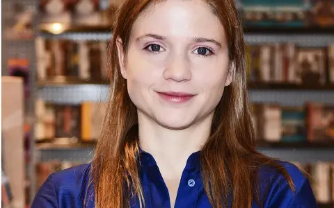 Eliza Rycembel, uśmiechnięta, w niebieskiej bluzce, na tle regałów z książkami. Jej życie prywatne jest tematem zainteresowania.
