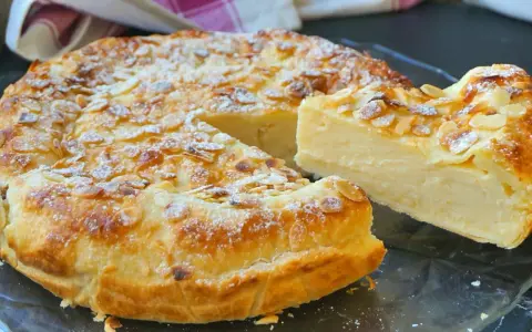 Tarta de hojaldre y crema pastelera, cubierta de almendras laminadas y espolvoreada con azúcar glas. ¡Un postre irresistible!