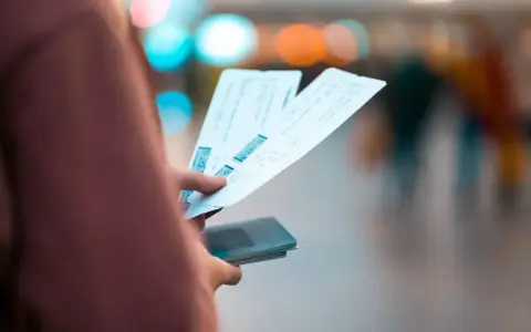 Dłoń trzymająca kilka biletów lotniczych i paszport.