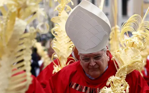 A bishop in red vestments and a white mitre holds a palm frond, surrounded by others. This scene marks Passion Sunday.