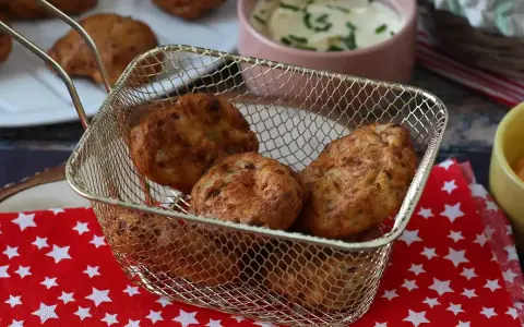 Gyldene chicken nuggets i en friteringskurv, nylagade i airfryer. Serveras med en krämig dipp.