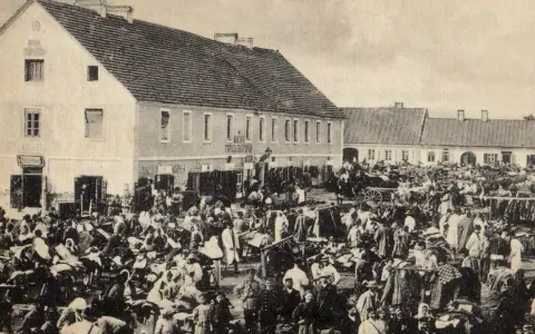 Tłum ludzi na targu w Biłgoraju, jakby żywcem wyjęty z legendy o tym mieście. W tle budynki i stragany.