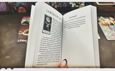 Mistycyzm i tarot marzyciela: otwarta księga z kartą "Czwórka Buław" i innymi kartami tarota.