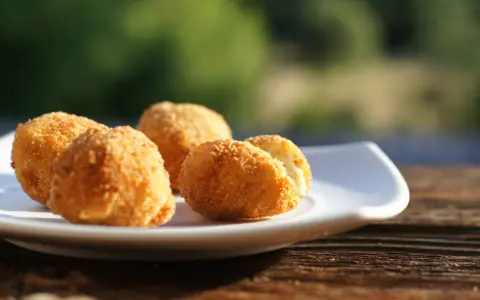 Croquetas caseras doradas y crujientes en un plato blanco, listas para disfrutar.