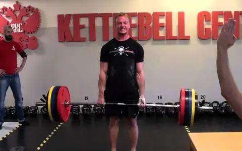 Man i gymmet förbereder sig för ett styrkelyft program. Han håller i en skivstång med vikter.