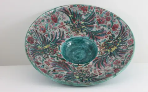 Plat décoratif en céramique, style Édouard Cazaux, orné d'oiseaux stylisés et de fleurs, avec un centre creux bleu turquoise.