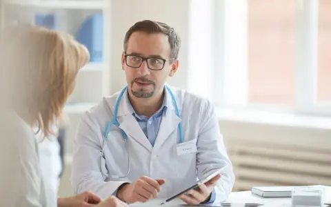 Arzt erklärt Patientin Ergebnisse, vielleicht den lipase wert, auf einem Tablet.