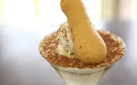Pyszne tiramisu w kieliszku, posypane kakao, z biszkoptem. Idealne, gdy szukasz, czym zastąpić amaretto.