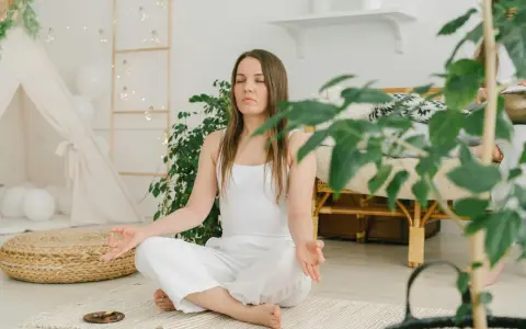 Frau in weißer Kleidung meditiert im Lotussitz. Eine sanfte Metta-Meditation-Anleitung textlich wäre hier passend.