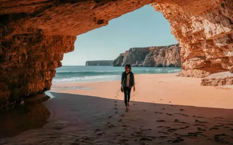 Frauen spazieren am Strand unter Felsbögen, ein perfekter Moment auf einer 14-tägigen Rundreise Portugal.