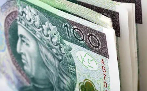 Stos banknotów 100 zł, symbolizujący premię uznaniową. Król na banknocie wygląda jakby cieszył się z dodatkowych pieniędzy.