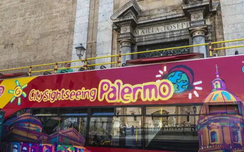 Autobus turistico rosso con scritta "City sightseeing Palermo". Un modo comodo per muoversi a Palermo e ammirare i monumenti.
