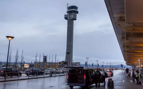 Wieża kontrolna na oslo lotnisko. Ludzie z bagażami wsiadają do vana.