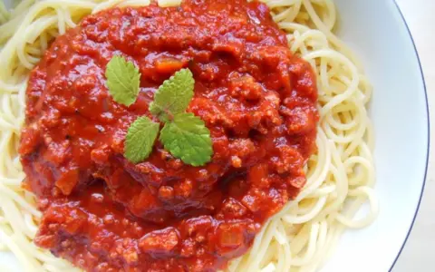 Spaghetti z bogatym sosem bolońskim i listkami mięty.