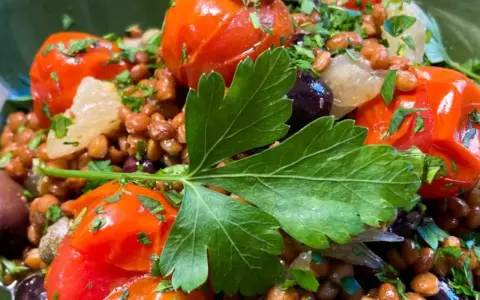 Ensalada de lentejas con tomates cherry, aceitunas negras y perejil fresco. Un plato saludable y lleno de sabor.