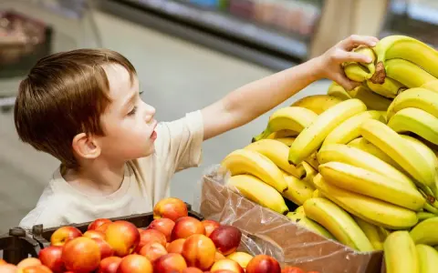 Chłopiec sięga po banana. Co zrobić, gdy dziecko kradnie w sklepie? Rozmowa i nauka uczciwości to klucz.