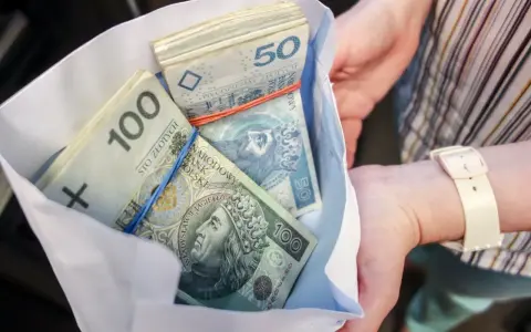 Koperta z plikiem banknotów 100 i 50 zł. Ile dać na 50 urodziny? Tyle pieniędzy to dobry prezent!