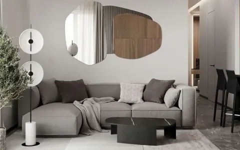 Nowoczesny salon z szarą sofą, geometrycznym lustrem i designerską lampą.