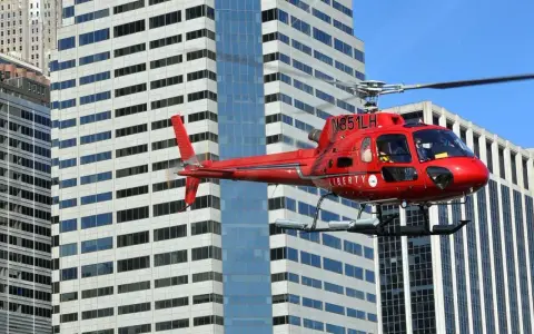 Czerwony helikopter Liberty przelatuje obok wieżowców. Zastanawiasz się, ile kosztuje lot helikopterem nad Nowym Jorkiem?
