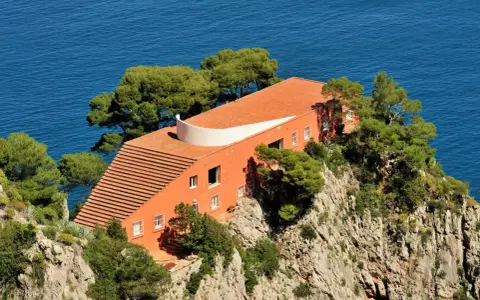 Villa Malaparte interni: arancione, sul mare, con scalinata e alberi.
