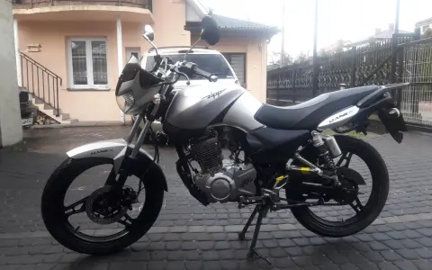 Srebrny Zipp Manic 125 na brukowanym podwórku, gotowy do jazdy.
