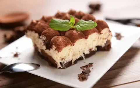 Pyszne tiramisu, posypane kakao i udekorowane miętą. Idealne na deser, choć warto pamiętać o jego tiramisu kcal.