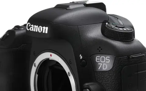 Czarne body aparatu Canon EOS 7D z widocznym obiektywem i pokrętłem trybów.