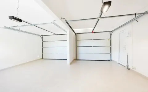 Dos puertas de garaje se abren a un espacio limpio y moderno, listo para pintar el garaje original.