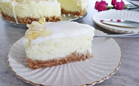 Pyszny sernik z mascarpone na kruchym spodzie, udekorowany płatkami migdałów. Idealny na deser.