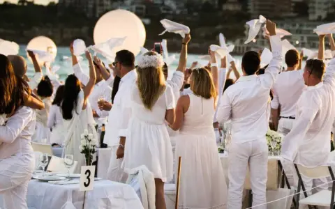 Festa in bianco: tutti vestiti di bianco per un evento elegante sulla spiaggia. Un'atmosfera magica con palloncini luminosi e tavoli apparecchiati.