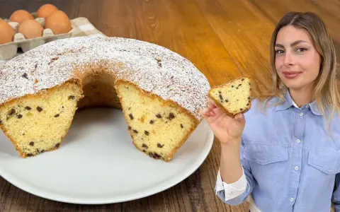 Un soffice ciambellone al bicchiere con gocce di cioccolato, spolverato di zucchero a velo, pronto per essere gustato.