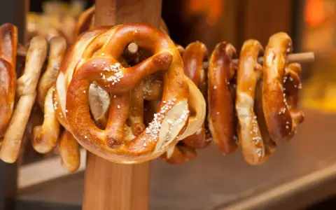 Des bretzels dorés, saupoudrés de gros sel, sont suspendus sur un support en bois. Ces spécialités lorraines invitent à la dégustation.