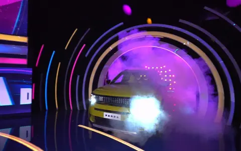 Żółty Fiat Panda wyjeżdża z dymu i świateł w kole fortuny.