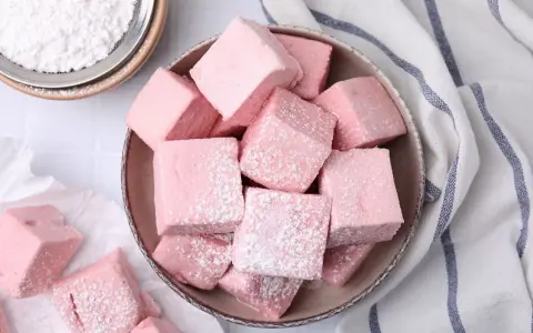 Dulces cubos rosados, como se hacen las nubes de azúcar, espolvoreados con azúcar glas.