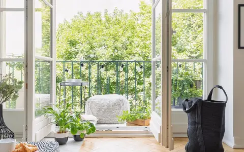 Balcones con plantas verdes y luces decorativas, invitando a disfrutar del exterior desde un acogedor interior.
