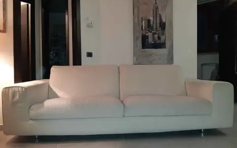 Un comodo divano bianco, perfetto per rilassarsi, con un quadro di New York alle spalle. I divani Bosal sono sinonimo di comfort.