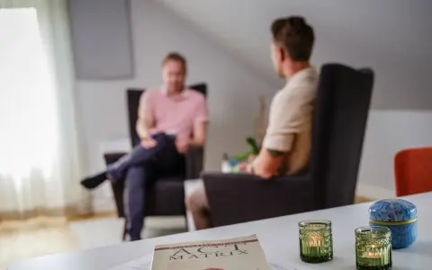 Två män i samtal i en lugn miljö. En bok om acceptance and commitment therapy svenska ligger på bordet.