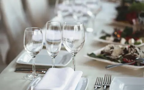 Trois verres à eau sont disposés sur une table dressée, prêts pour un repas.