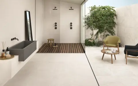 Un bagno moderno con vasca in pietra, doccia a filo pavimento e un'area relax esterna. Il pavimento casa mare crea un'atmosfera rilassante.